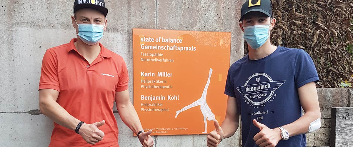 Foto von Benjamin Kohl und Sportler vor dem Eingangsschild der Praxis state of balance